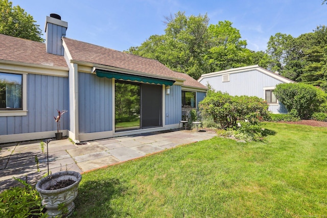 957A Heritage Vlg, Southbury, CT 06488 - back of property with a shingled roof, a lawn, a patio area, and a chimney