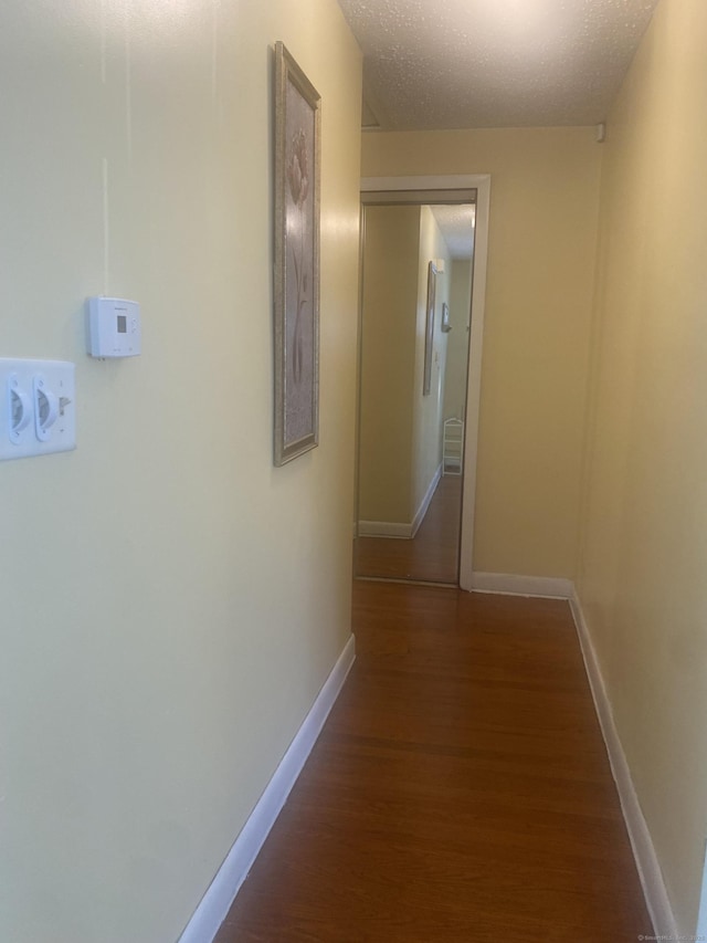 hall with dark wood-type flooring and a textured ceiling