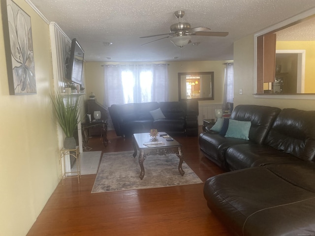 living room with dark wood-type flooring, ceiling fan, and a textured ceiling