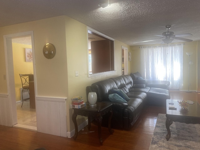 living room with hardwood / wood-style flooring, ceiling fan, and a textured ceiling