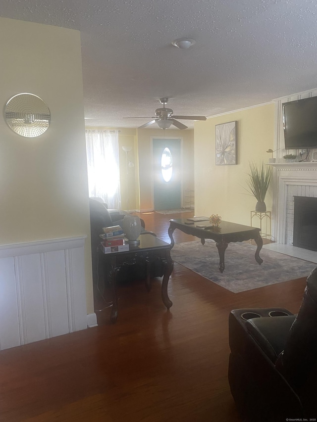 rec room featuring ceiling fan, a fireplace, hardwood / wood-style floors, and a textured ceiling