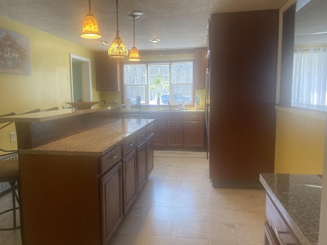 kitchen with pendant lighting, a breakfast bar, kitchen peninsula, and a textured ceiling