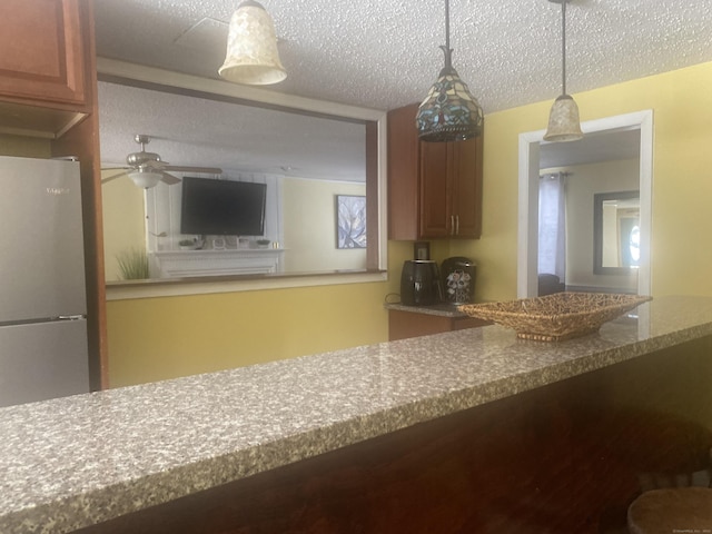 kitchen with ceiling fan, decorative light fixtures, a textured ceiling, and refrigerator