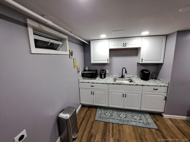 kitchen with white cabinetry, dark hardwood / wood-style flooring, sink, and light stone counters