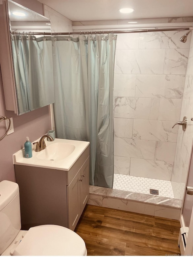 bathroom with hardwood / wood-style flooring, vanity, curtained shower, a baseboard radiator, and toilet