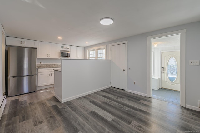 kitchen with a baseboard heating unit, stainless steel appliances, dark hardwood / wood-style floors, and white cabinets