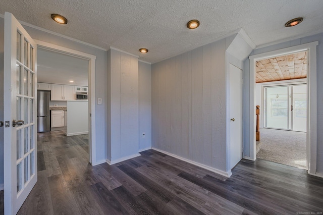 unfurnished room featuring crown molding, dark hardwood / wood-style floors, wooden walls, and a textured ceiling