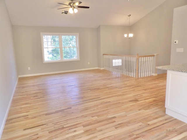 spare room with lofted ceiling, ceiling fan with notable chandelier, and light hardwood / wood-style flooring