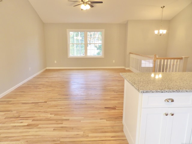 kitchen featuring ceiling fan with notable chandelier, white cabinets, hanging light fixtures, light stone countertops, and light hardwood / wood-style flooring