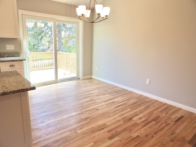 unfurnished dining area featuring light wood-type flooring and an inviting chandelier