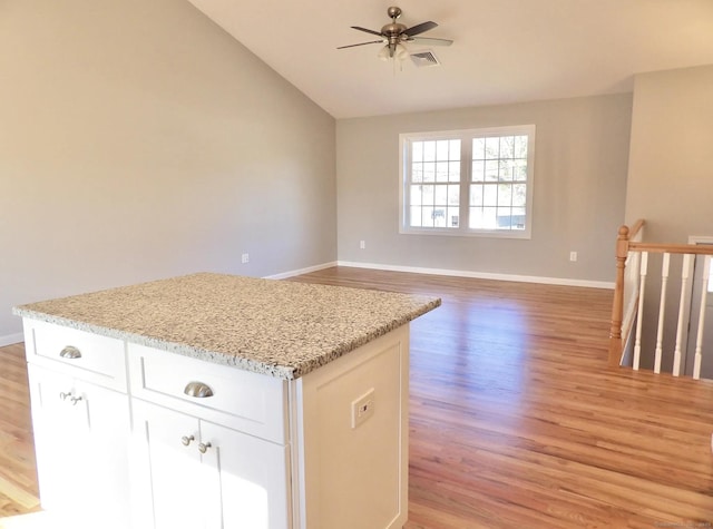 kitchen with light stone counters, lofted ceiling, light hardwood / wood-style floors, and white cabinets