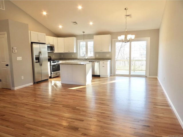 kitchen with stainless steel appliances, decorative light fixtures, a center island, and white cabinets