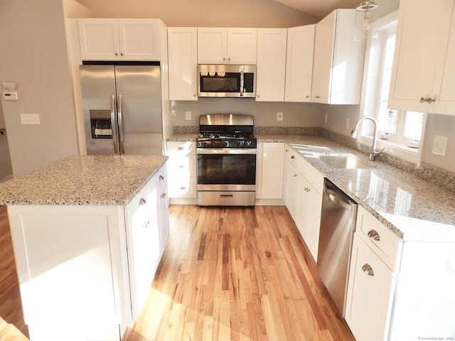 kitchen featuring stainless steel appliances, light stone countertops, a kitchen island, and white cabinets