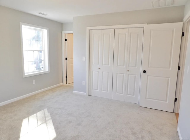 unfurnished bedroom with light carpet and a closet