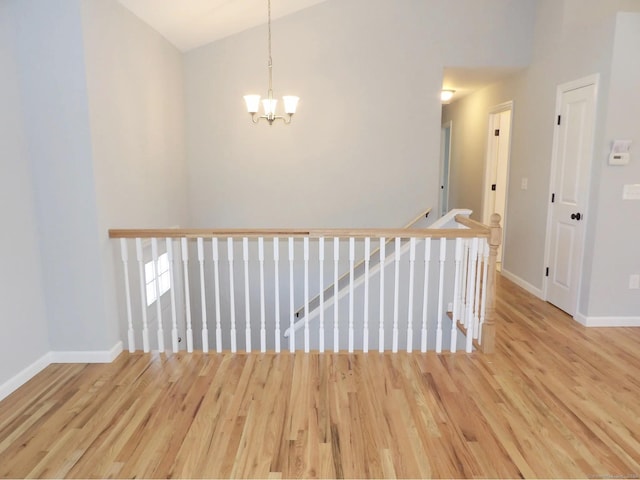 hall with hardwood / wood-style floors, a notable chandelier, and high vaulted ceiling