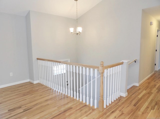 stairs with vaulted ceiling, a chandelier, and hardwood / wood-style floors