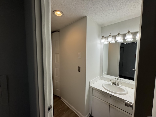 bathroom featuring hardwood / wood-style flooring, vanity, and a textured ceiling