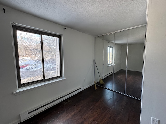 unfurnished bedroom with a baseboard heating unit, a textured ceiling, and a closet