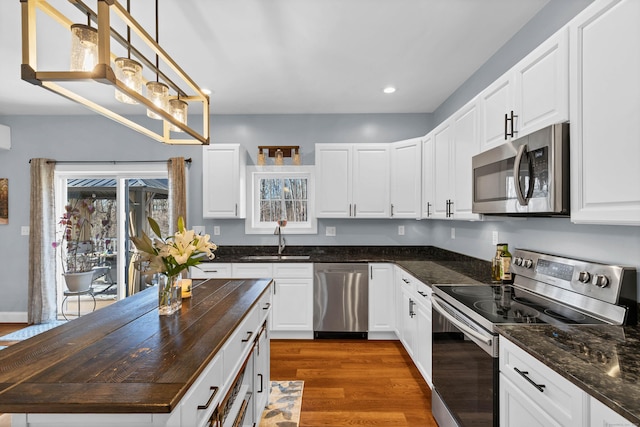 kitchen with dark hardwood / wood-style floors, decorative light fixtures, white cabinetry, sink, and stainless steel appliances