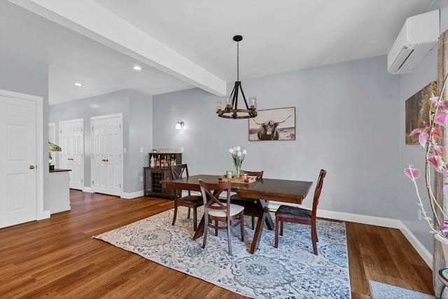 dining room featuring dark wood-type flooring, a wall mounted AC, a notable chandelier, and beam ceiling