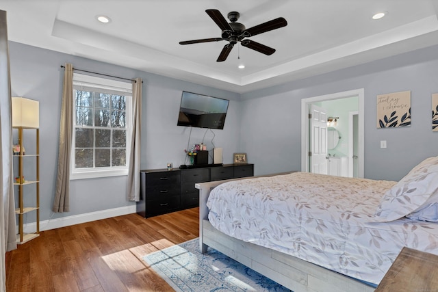 bedroom featuring hardwood / wood-style flooring, ceiling fan, and a tray ceiling