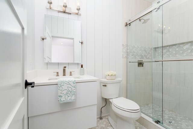 bathroom featuring a shower with door, vanity, and toilet