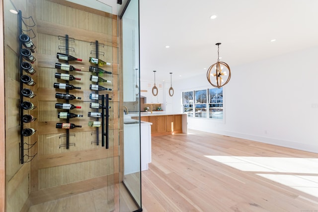 wine cellar with an inviting chandelier and light hardwood / wood-style floors