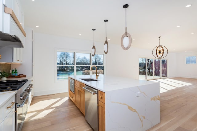 kitchen featuring appliances with stainless steel finishes, pendant lighting, white cabinetry, sink, and a spacious island