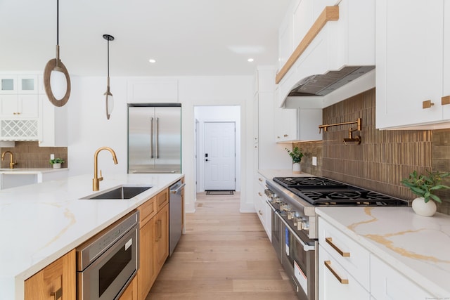 kitchen with white cabinetry, built in appliances, light stone countertops, and hanging light fixtures