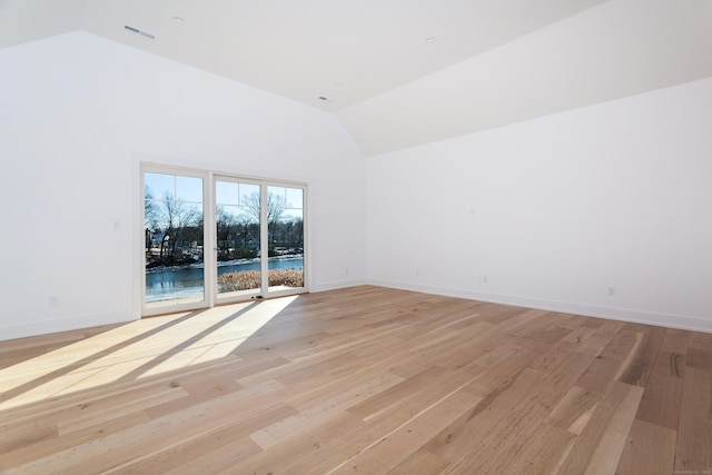 empty room with high vaulted ceiling and light hardwood / wood-style flooring