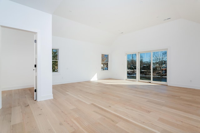 unfurnished living room with high vaulted ceiling, a healthy amount of sunlight, and light wood-type flooring