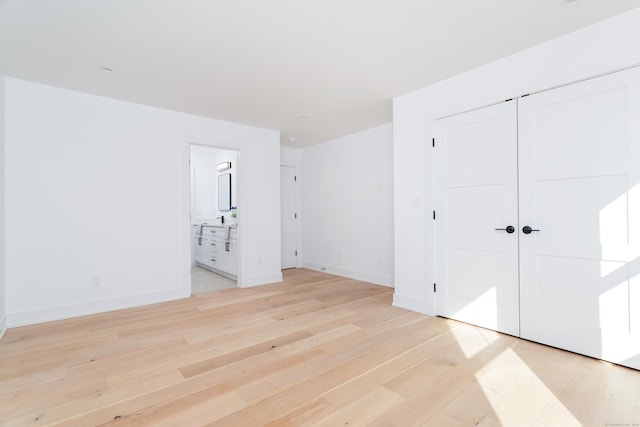 unfurnished bedroom featuring connected bathroom and light wood-type flooring