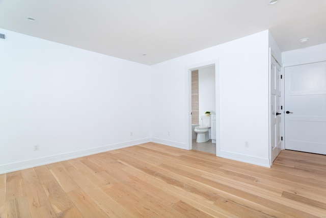 unfurnished bedroom with connected bathroom and light wood-type flooring