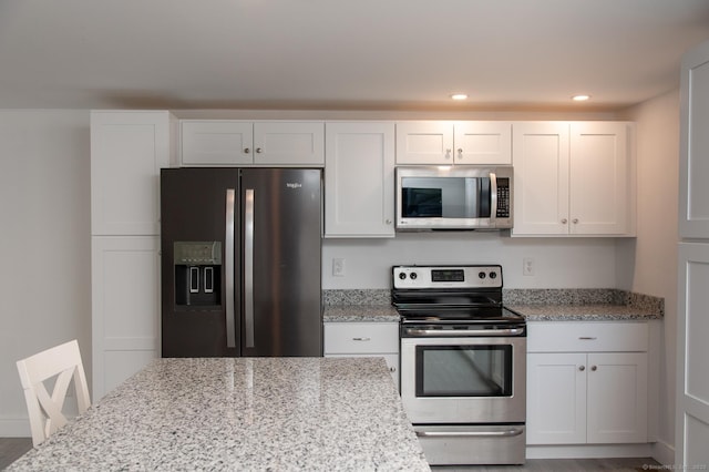 kitchen with white cabinetry, appliances with stainless steel finishes, and light stone counters