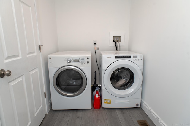 clothes washing area with dark wood-type flooring and washing machine and clothes dryer