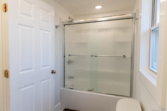 bathroom featuring bath / shower combo with glass door and toilet