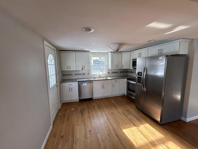 kitchen featuring stainless steel appliances, sink, white cabinets, and light hardwood / wood-style floors