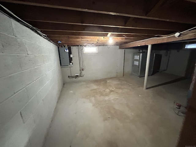 basement featuring electric panel and heating unit