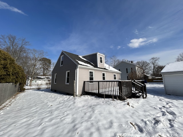 snow covered rear of property with a deck