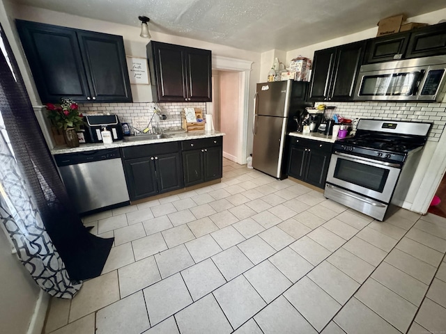 kitchen featuring sink, tasteful backsplash, a textured ceiling, light tile patterned floors, and stainless steel appliances