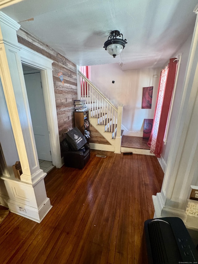 staircase with ornate columns, hardwood / wood-style flooring, and wooden walls