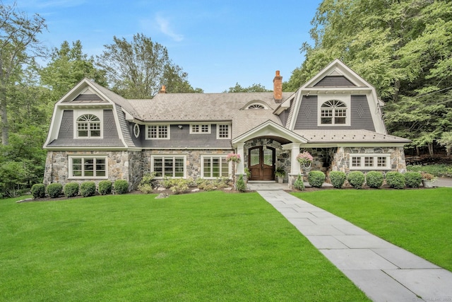 shingle-style home with a front lawn, stone siding, and a gambrel roof