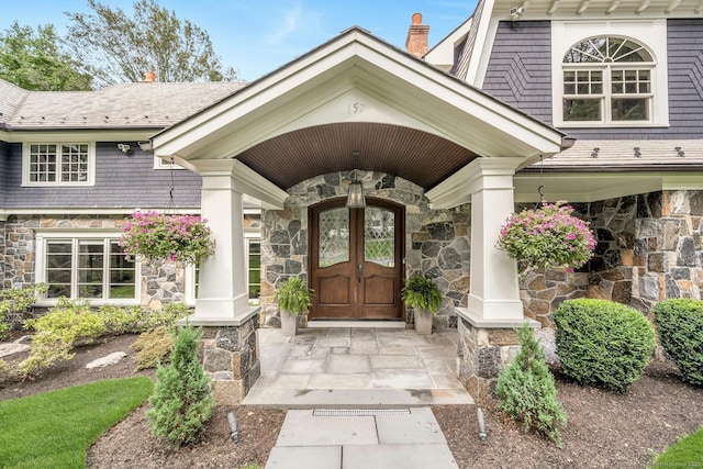 view of exterior entry featuring covered porch and stone siding