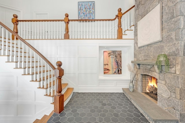 stairway with a decorative wall and a stone fireplace