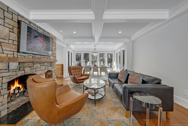 living room with coffered ceiling, ornamental molding, beamed ceiling, wood finished floors, and a stone fireplace