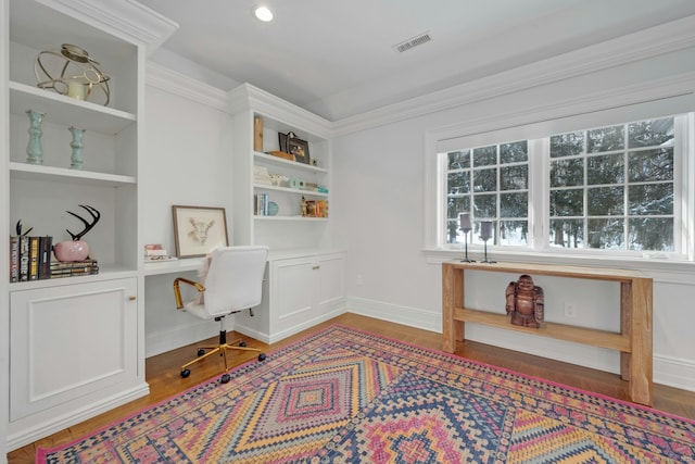 office space featuring baseboards, visible vents, built in desk, and wood finished floors