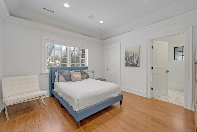 bedroom with ornamental molding, wood finished floors, visible vents, and baseboards