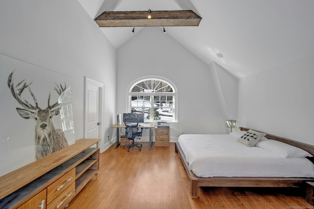 bedroom featuring light wood finished floors, baseboards, high vaulted ceiling, and beam ceiling