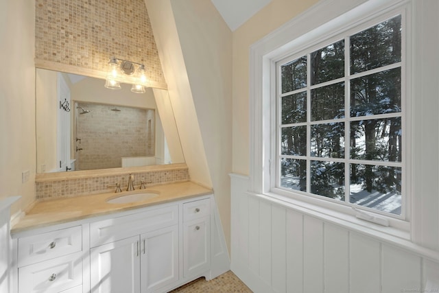 full bathroom with a wainscoted wall, a tile shower, decorative backsplash, and vanity