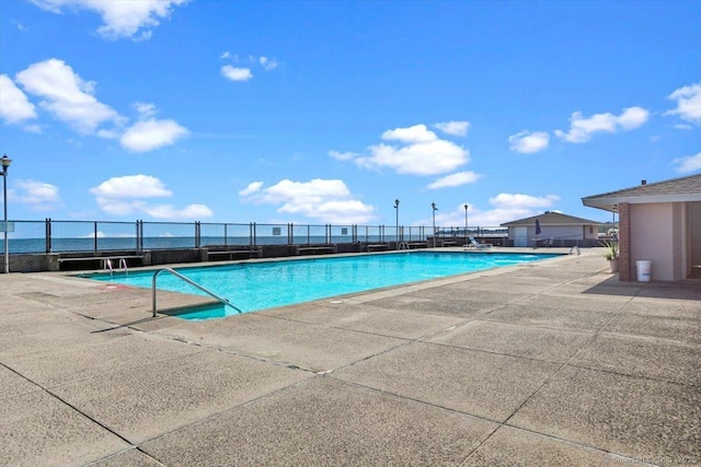 view of pool with a water view and a patio area